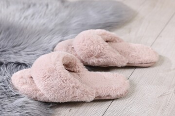 Pink soft slippers on light wooden floor at home, closeup