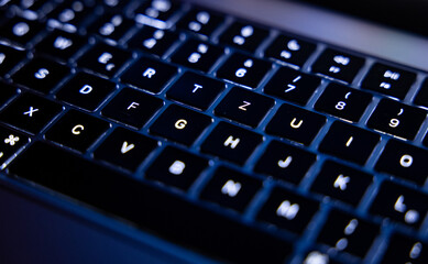 Close-up of illuminated computer keyboard. The keys are black with white letters and characters.