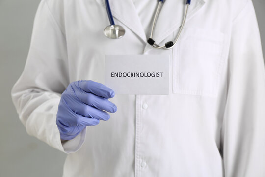 Endocrinologist with stethoscope holding card on grey background, closeup