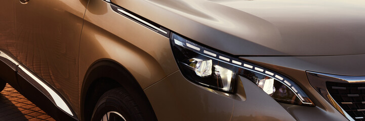 Golden SUV by sunset. Close up of the headlights. - obrazy, fototapety, plakaty