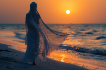 A woman in a white dress is walking on the beach at sunset