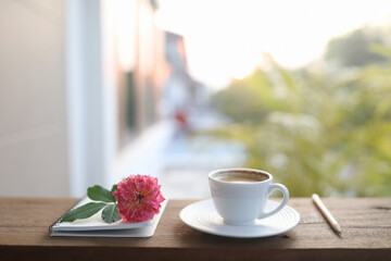 ceramic coffee cup and a white vase of rose flowers and notebooks