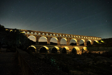 illuminated ancient Roman aqueduct Pont du Gard near Languedoc, France, built as part of the infrastructure for water supply of the roman empire.