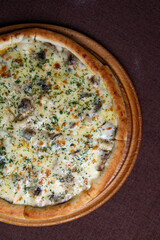 Top view of a delicious pizza with mushrooms and cheese on a wooden board.