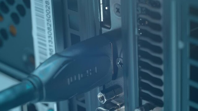 A man's hand inserts and removes a HDMI wire into the back of a computer. Closeup. Macro