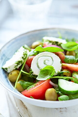 Summer Salad with Cream Cheese, green Olives, Tomatoes and fresh Basil. Bright wooden background. Close up	