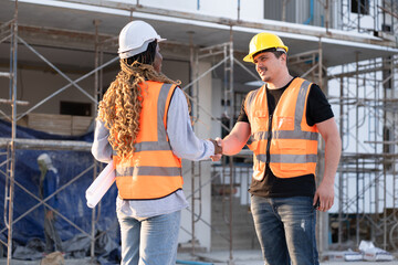 Worker Caucasian engineer man hand shake with African woman worker at construction site	 - 765060312