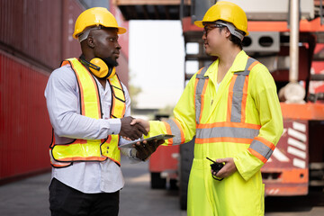 Portrait Asia logistic engineer man worker or foreman hand shake with African foreman use tablet computer working at container site	 - 765060348