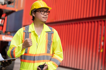 Confident Asia logistic engineer man worker or foreman working with walkie talkie at container site	 - 765060359