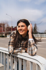 One young girl is listening to music on her wireless headphones and enjoying the sun outdoors	