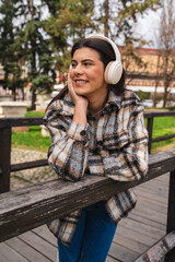 One young girl is listening to music on her wireless headphones and enjoying the sun outdoors	