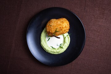 Top view Crispy fried chicken cutlet Kiev style with mashed potatoes on a black plate