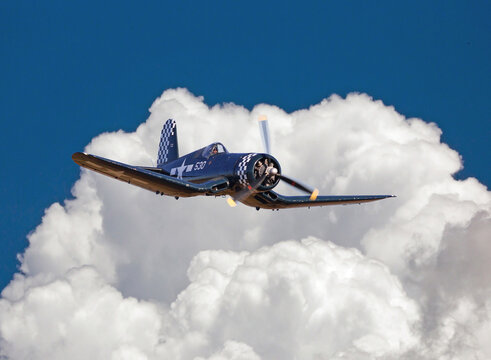 Vought F4U Corsair Fighter in Flight with Puffy White Clouds