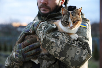 Ukrainian soldier with stray cat outdoors, closeup