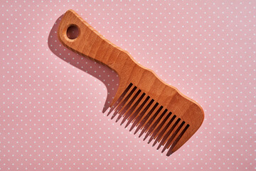 Wooden comb on a pink polka dot background.