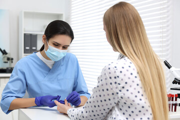 Laboratory testing. Doctor taking blood sample from patient at white table in hospital