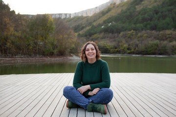 Fototapeta premium Overweight woman rests on the lake and admires beautiful views of the landscape