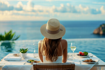 Dinner overlooking the sea in a luxury hotel. A woman in a straw hat sitting at a romantic table overlooking the sea or ocean
