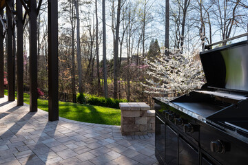 Backyard garden view with a black gas grill in springtime. Outdoors cooking concept.