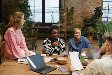 Portrait of diverse successful business team working together at meeting table in green office and...