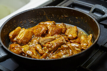 Chicken pieces in a sauce with paprika and turmeric in gravy in a frying pan