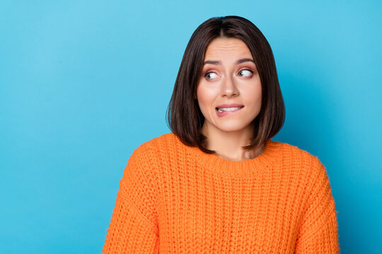 Portrait of attractive puzzled brown-haired girl biting lip thinking copy space isolated over bright blue color background