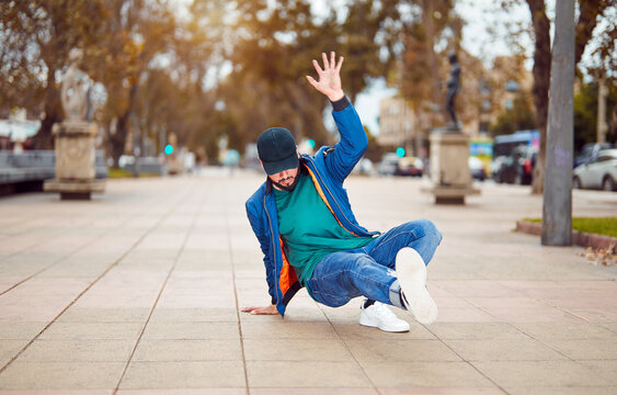breakdancer guy performing downrock or floor based footwork stunt on the street