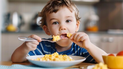 funny boy has Breakfast crumbled eggs alone with a spoon and make a mess, cute funny boy eating...