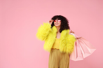 Happy young woman with shopping bags on pink background. Space for text