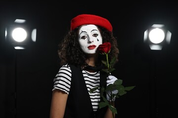 Young woman in mime costume with red rose performing on stage