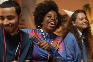 Portrait of Black young woman laughing with genuine emotion while enjoying party with friends at...