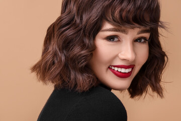 Naklejka premium Beautiful young woman with wavy hairstyle on beige background