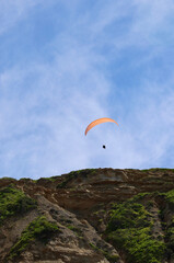 paraglider soaring above the coastline