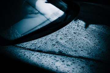 A beautiful passenger car is covered in rain drops after the rain in the evening at dusk.