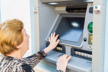 Older pensioner woman using an ATM