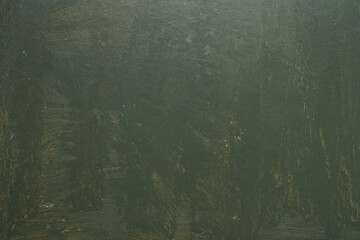 Old textured wall unevenly painted with green paint with stains and scratches