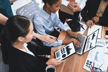 Multiracial analyst team use BI Fintech software to analyze financial data on meeting table. Financial dashboard data display on laptop screen with analyzed chart for marketing indication. Concord