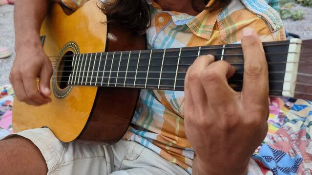 A person playing classical guitar while relaxing outdoors.