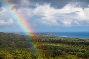 Hawaiian Rainbow over Poipu, Kauai. The view from a coffee plantation in Kalaheo of a beautiful colorful rainbow over the popular tourist area of Poipu and the Pacific Ocean. - 765123567