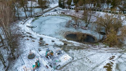 Drone photography of iced up pond in public park and ducks in it during winter day