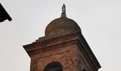 Campanile di una chiesa visto dal basso che si staglia nel cielo grigio autunnale - obrazy, fototapety, plakaty
