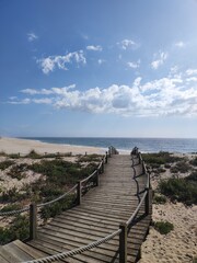 A boardwalk that leads you to the sandy shores of Portugal, where the Atlantic ocean meets the white sand.
