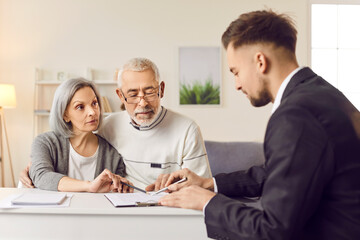 Elderly couple finalizes purchase of new property signing contract with realtor. Senior couple...