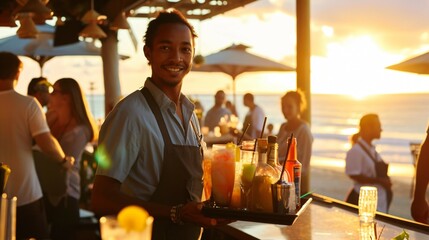 Happy waiter with a tray of cocktails at a beach bar during sunset.