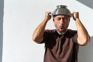 bearded cheerful man with a colander on his head. cheerful portraits of a man with a colander