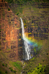 Waipo’o Falls Flashing a Beautiful Rainbowin Waimea Canyon, Kauai, Hawaii. Waipo'o Falls, a glorious two-tier, 800 foot waterfall, cascades into the deep and colorful gorge of the Waimea Canyon below.