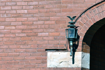 A wall lamp against a red brick wall.
