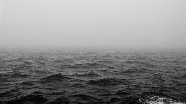 a black and white photo of a large body of water with a boat in the middle of the water on a foggy day.