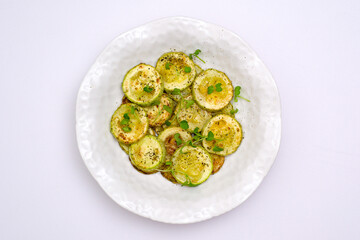 Fried zucchini with lemon zest and thyme on white background. Top view.