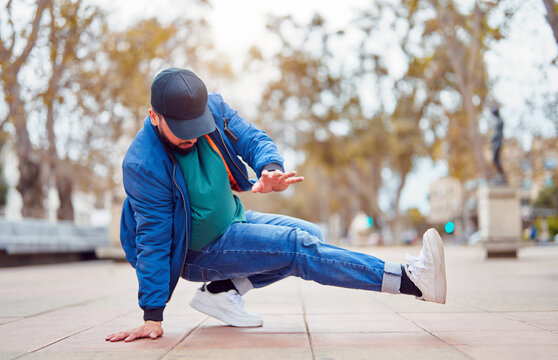 breakdancer guy performing downrock or floor based footwork stunt on the street